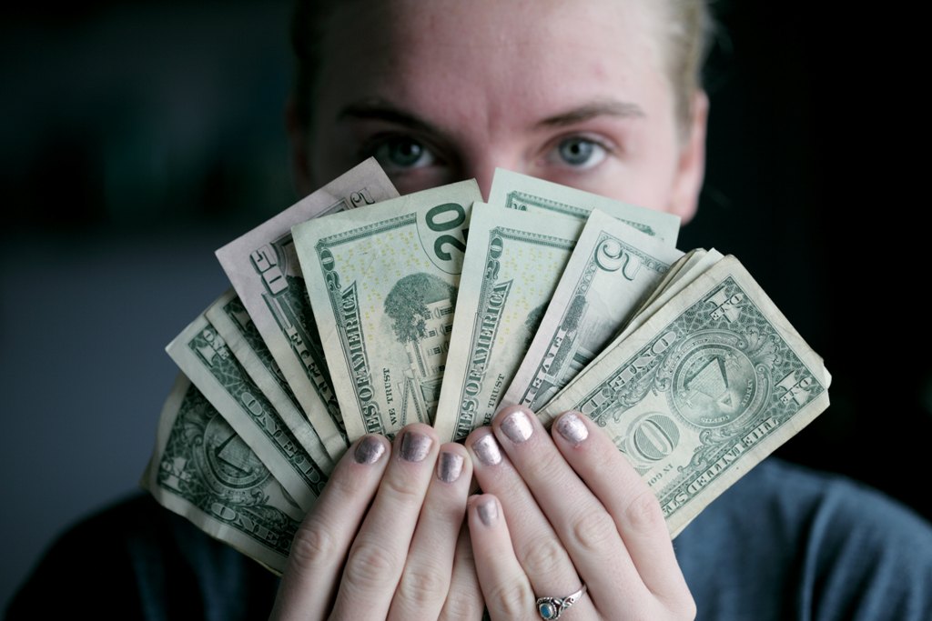 Kobieta trzymająca dolary rozłożone w wachlarz